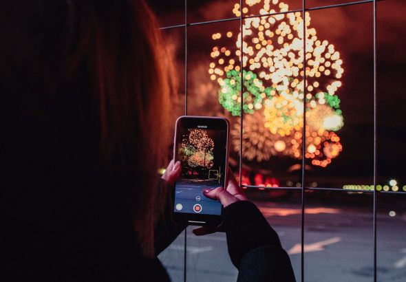 woman taking a picture of fireworks during night